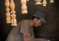 A man sitting at a table working on a piece of wood