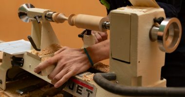 A woodworker uses a lathe to shape wood.
